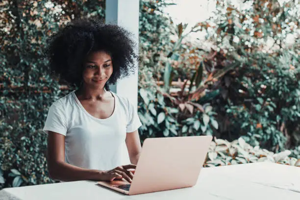 Photo of Young woman working on laptop at home in balcony.