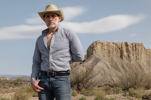 Adult man in cowboy hat in desert against rock and sky. Almeria, Spain