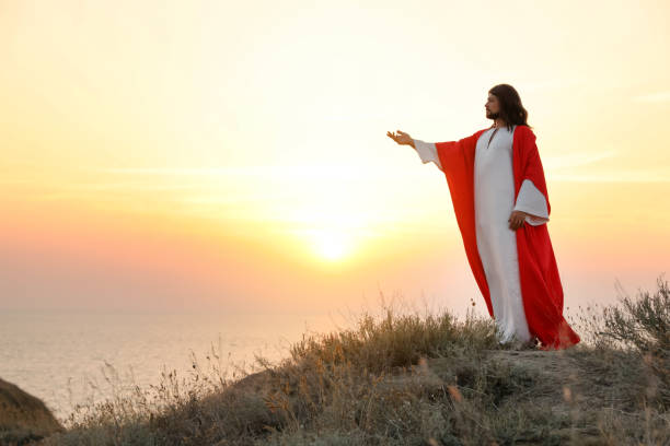 istock Jesus Christ raising hand on hills at sunset. Space for text 1398266609