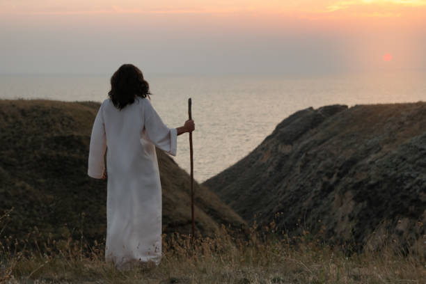 istock Jesus Christ with stick on hills at sunset, back view. Space for text 1398266629