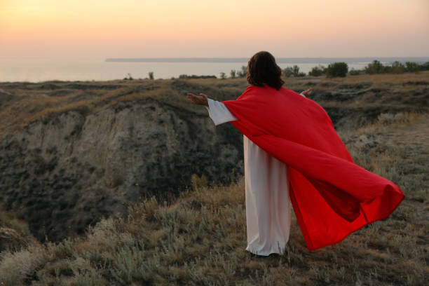 istock Jesus Christ raising hands on hills at sunset, back view. Space for text 1398266728