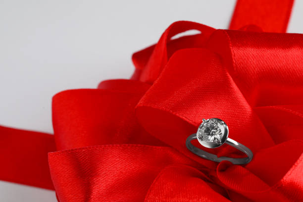 istock Beautiful red bow and engagement ring on white background, closeup 1398266734