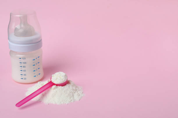 istock Powdered infant formula with scoop and feeding bottle on pink background, space for text. Baby milk 1398266856