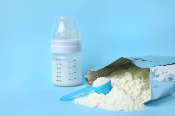 istock Bag of powdered infant formula, feeding bottle and scoop on light blue background, space for text. Baby milk 1398267066
