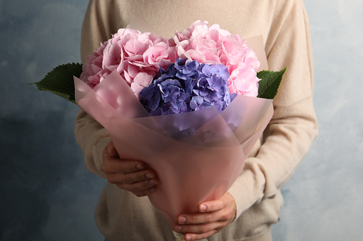 Woman with bouquet of beautiful hortensia flowers on color background, closeup
