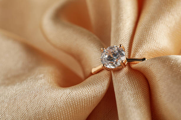 istock Beautiful engagement ring with gemstone on beige fabric, closeup 1398267275