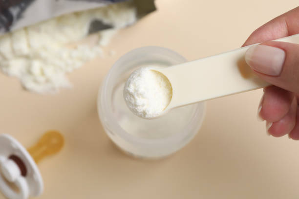 istock Woman preparing infant formula on beige background, top view. Baby milk 1398268024