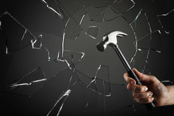 istock Woman breaking window with hammer on dark grey background, closeup 1398268740