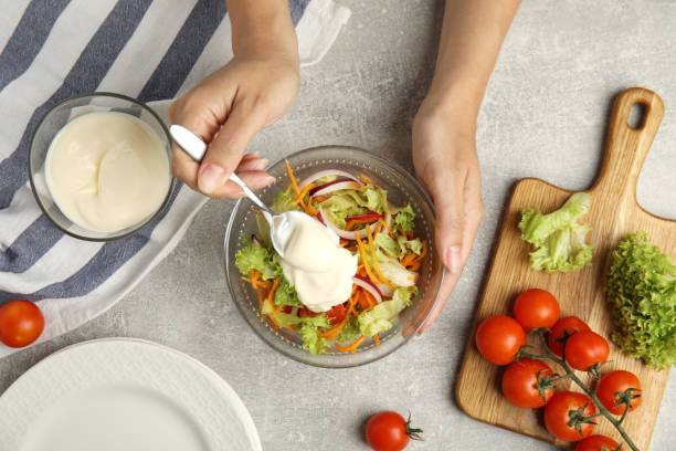 istock Woman adding mayonnaise to delicious salad at grey table, top view 1398268865