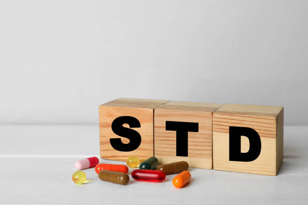 略語stdは、白い木製のテーブルの上の丸薬の近くの立方体で作られました - sex object ストックフォトと画像