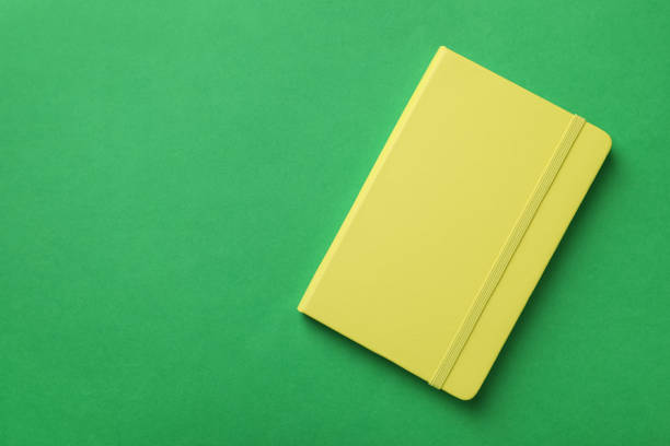 istock New stylish planner with hard cover on green background, top view. Space for text 1398269630