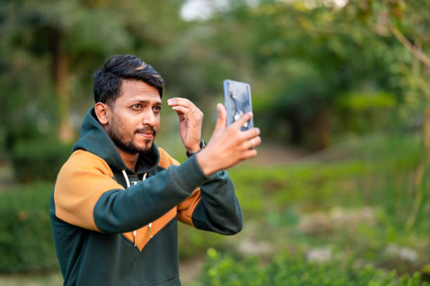 istock Handsome Indian Man Taking Selfie With Mobile Phone in park 1398273360