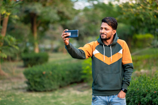 istock Handsome Indian Man Taking Selfie With Mobile Phone in park 1398273885