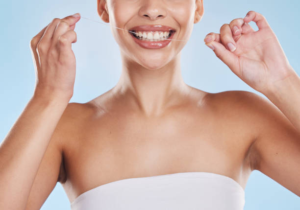 istock Beautiful young mixed race woman using dental floss isolated in studio against a blue background. Attractive female flossing her teeth for oral and dental hygiene and gum health, and a big smile 1398276965