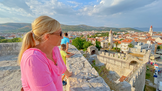 Mature woman wearing sunglasses and looking at town in Trogir, Croatia, Europe.