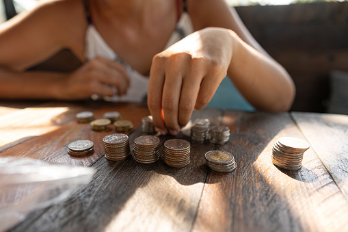 Unrecognizable Caucasian woman counting Thai baht coins