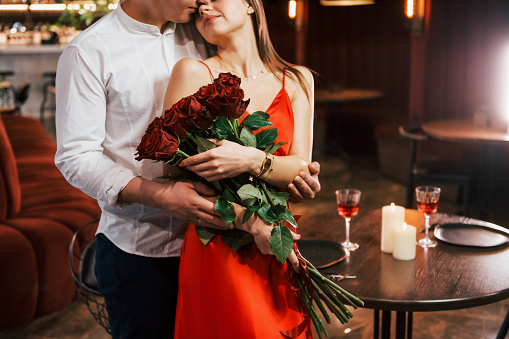 Man giving beautiful flowers. Romantic couple have dinner in the restaurant.