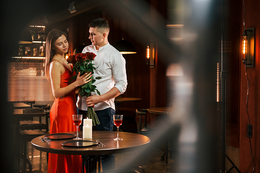 Standing with flowers. Romantic couple have dinner in the restaurant.