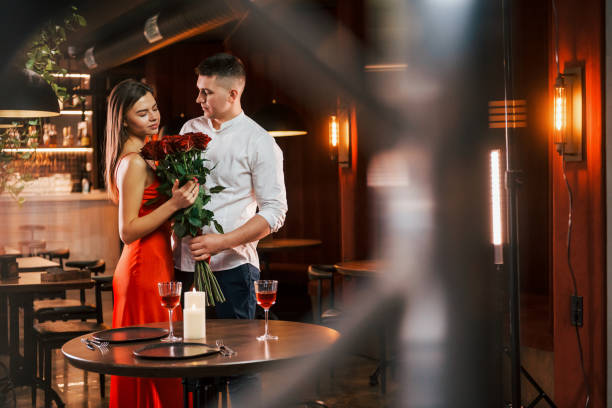 istock Standing with flowers. Romantic couple have dinner in the restaurant 1398279246