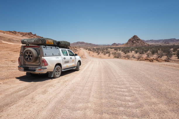 Erongo region, Namibia - October 11, 2021: Off-road vehicle on a dirt road in the Erongo Region in direction of Spitzkoppe. Fascinating loneliness on the road trip across Namibia.