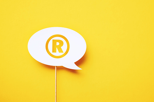 Register symbol written circular white chat bubble sitting on yellow background. Horizontal composition with copy space.