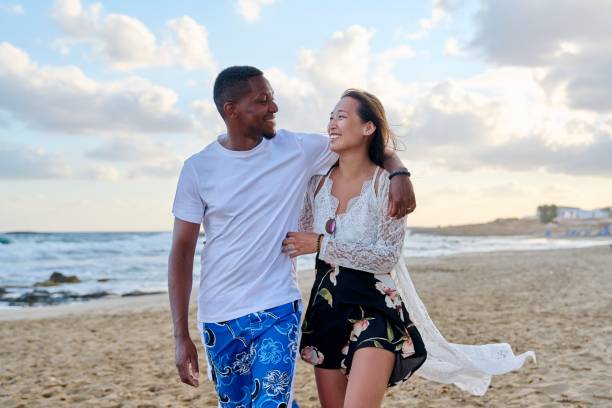 istock Young happy couple walking on the beach holding hands. 1398281046