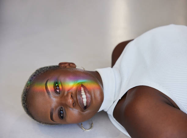 istock Smiling woman with rainbow colored light refracting onto her face 1398281154