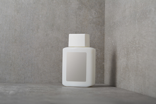 Face or body care cosmetic product bottle with blank label on concrete background