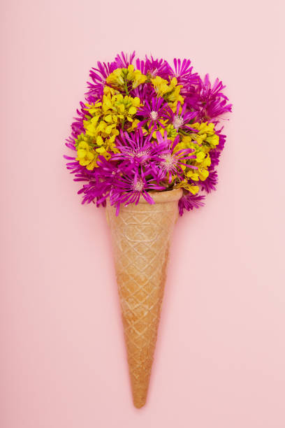 istock Fresh wildflowers in ice cream cone on pink background flat lay 1398283301