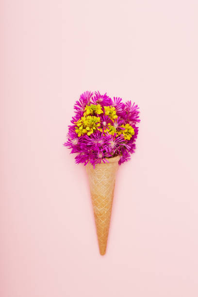 istock Fresh wildflowers in ice cream cone on pink background flat lay 1398283342