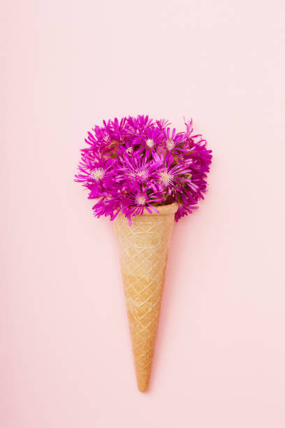istock Fresh wildflowers in ice cream cone on pink background flat lay 1398283365