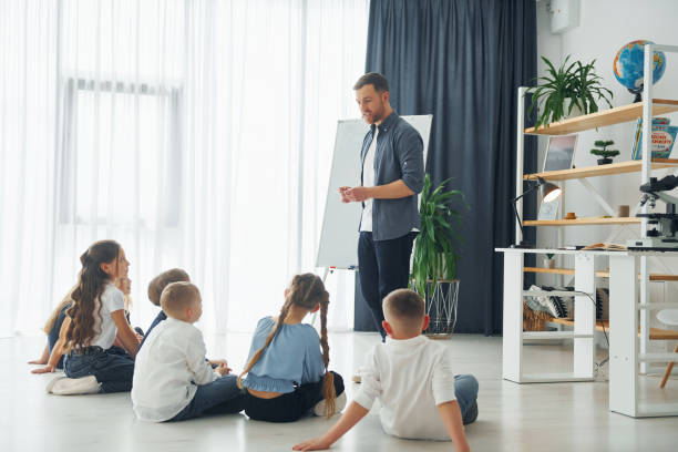 istock Standing and explaining lesson by using whiteboard. Group of children students in class at school with teacher 1398283850