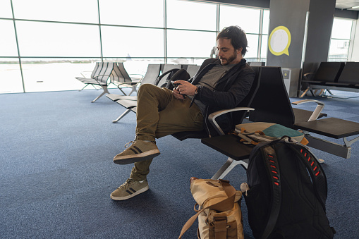 Side view of Caucasian man using mobile phone at the airport departure area