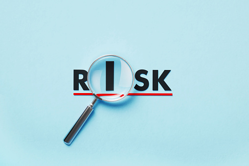 Magnifier forming risk word on blue background. Horizontal composition with copy space. Risk concept.