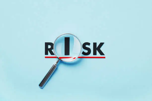 Photo of Magnifier Forming Risk Word On Blue Background