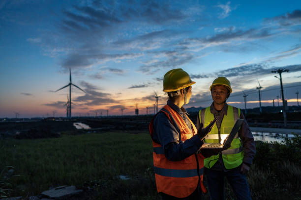 istock Two engineers hold computers at the wind power airport to discuss data 1398285930
