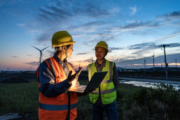 istock Two engineers hold computers at the wind power airport to discuss data 1398285933