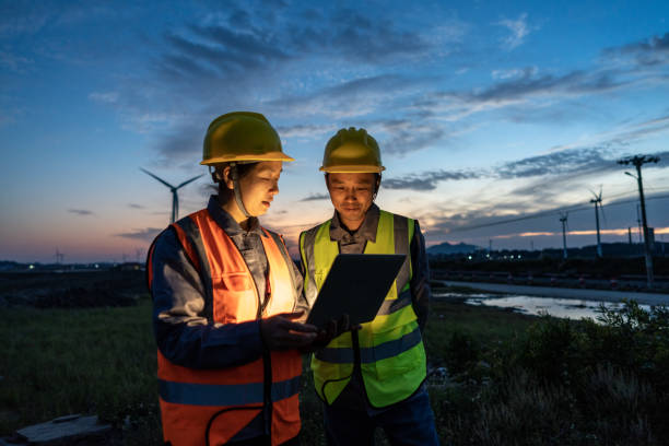 istock Two engineers hold computers at the wind power airport to discuss data 1398286164