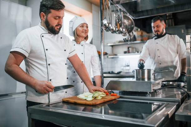 istock Team making salad. Professional chef preparing food in the kitchen 1398287366