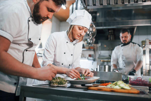 istock Team making salad. Professional chef preparing food in the kitchen 1398287375