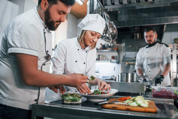 istock Team making salad. Professional chef preparing food in the kitchen 1398287378