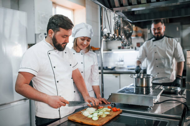 istock Team making salad. Professional chef preparing food in the kitchen 1398287392