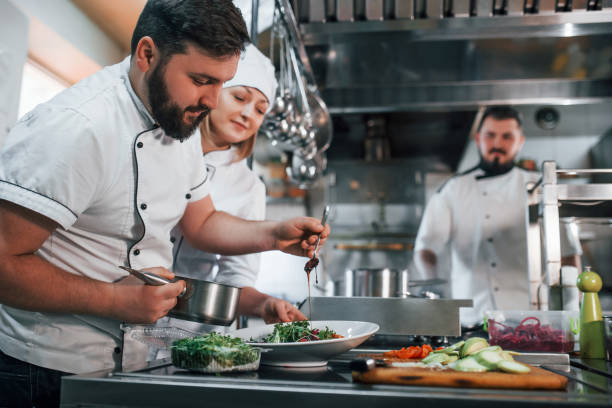 istock Team making salad. Professional chef preparing food in the kitchen 1398287404