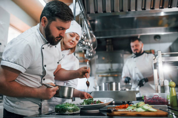 istock Three people. Making vegan salad. Professional chef preparing food in the kitchen 1398287413