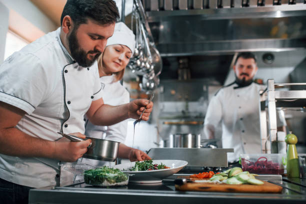 istock Three people. Making vegan salad. Professional chef preparing food in the kitchen 1398287414