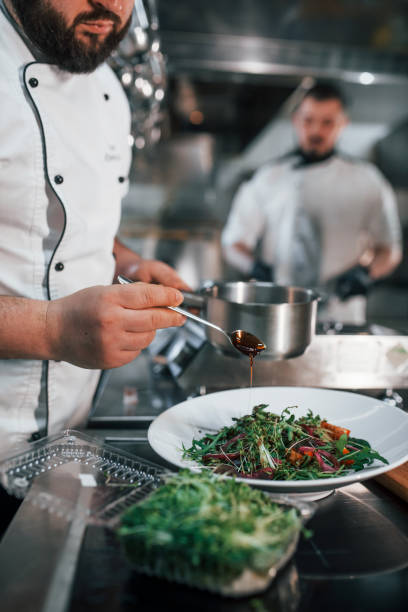 istock Pouring ingredients. Professional chef preparing food in the kitchen 1398287438