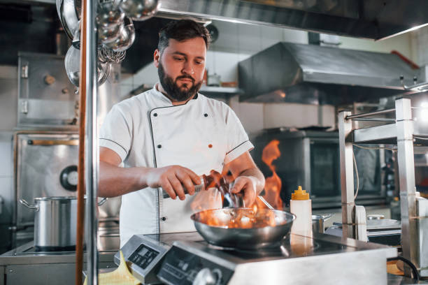 istock Cooking meal by using flames. Professional chef preparing food in the kitchen 1398287540