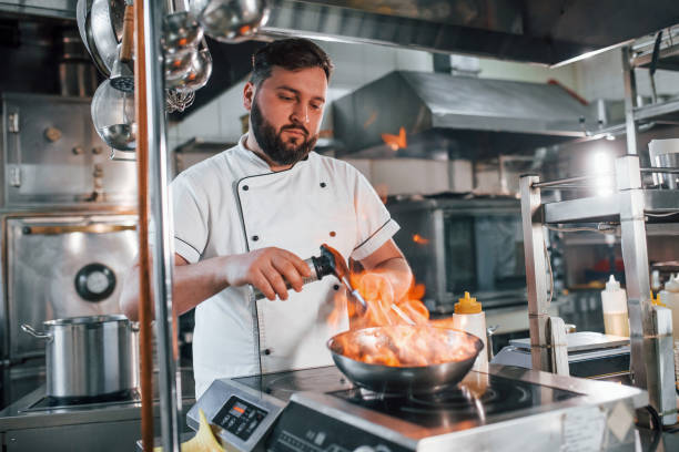 istock Cooking meal by using flames. Professional chef preparing food in the kitchen 1398287550