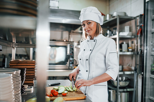 Woman making salad. Professional chef preparing food in the kitchen.