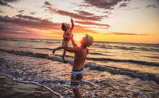 A happy family at the beach a father and baby daughter having fun at sunset